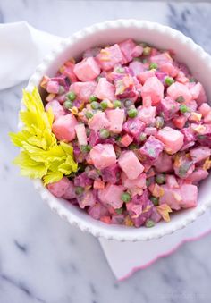 a white bowl filled with food on top of a marble counter next to a yellow flower