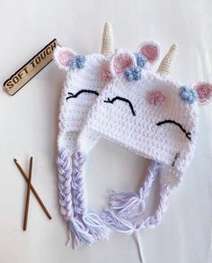 a crocheted unicorn hat and knitting needles