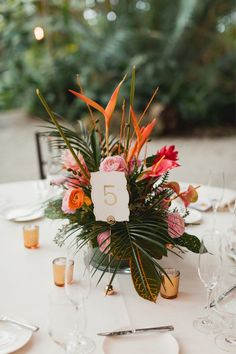 an arrangement of flowers and greenery is displayed on the table at this wedding reception