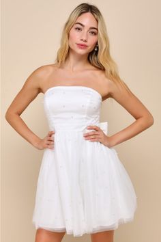 Making memorable moments will be all the better when you're wearing the Lulus Stunning Time White Tulle Pearl Strapless Bow Mini Dress! Gleaming faux pearls adorn sheer mesh tulle as it shapes this fun and fabulous dress that features a strapless, seamed bodice (with hidden no-slip strips) and a straight neckline. A high, banded waist sits atop a twirl-worthy, skater-style skirt that finishes at flirty mini hem. Turn around to reveal a sleek, oversized satin bow with long elegant sashes that len Embellished Tulle Mini Dress, Summer Bridesmaid Strapless Tulle Dress, Summer Embellished Tulle Dresses, Strapless Tulle Mesh Dress For Prom, Strapless Tulle Mesh Prom Dress, Strapless Mesh Dress For Spring Prom, Summer Tulle Mesh Dress With Sweetheart Neckline, Summer Tulle Mini Dress With Sweetheart Neckline, White Tulle Mesh Dress For Spring