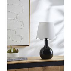 a black table lamp sitting on top of a wooden dresser next to a white wall