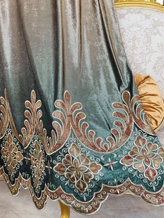 an ornately decorated bed with gold and green covers on it's headboard