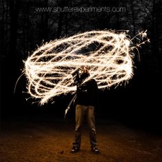 a person standing in the dark with some sparklers on their head and hands behind them