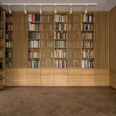 an empty room with bookshelves full of books and wood flooring on the walls