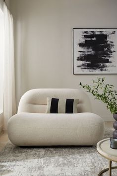 a living room with a white couch and black and white artwork on the wall behind it