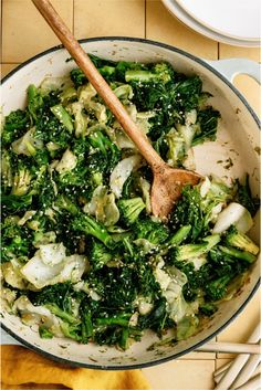 broccoli and onions in a pan with a wooden spoon