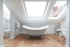 a white bath tub sitting under a skylight in a bathroom