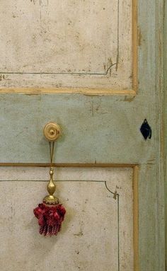 an old door with a small red object hanging from it's side and the handle