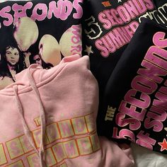 pink and black sweatshirts laying on top of each other with the tops printed in different colors