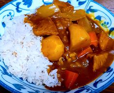 a blue and white plate topped with rice and curry