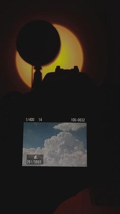 a camera with the sun setting behind it and clouds in the sky, as seen from below