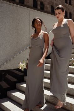 two women in long dresses standing on steps