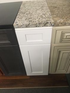 a kitchen counter top with white cabinets and black appliances in the corner, next to a brown door