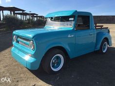 an old blue pick up truck parked in a parking lot