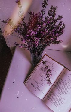 an open book sitting on top of a table next to a vase filled with flowers