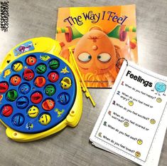 a book and toy sitting on top of a table next to a game board with the words feelings