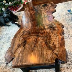 a large wooden table sitting on top of a carpeted floor next to a black dog