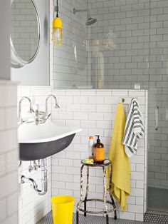 a white tiled bathroom with yellow and black accessories