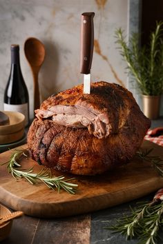 A large, roasted pork shoulder on a wooden cutting board with a knife inserted on top, surrounded by rosemary sprigs. Porchetta Recipe Italian, Streets Of Italy, Recipe Italian