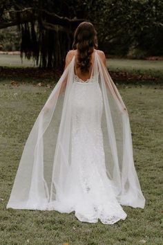 the back of a bride's wedding dress, with her veil blowing in the wind