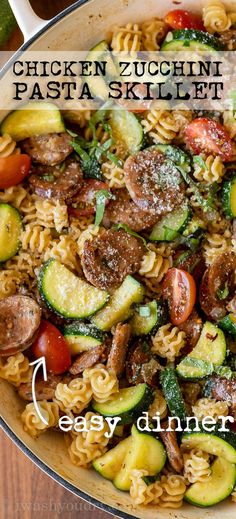 a skillet filled with pasta, sausage and zucchini