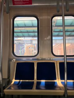 the inside of a subway car with two windows and blue seat covers on each side