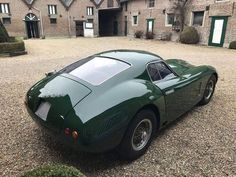 a green sports car parked in front of a brick building