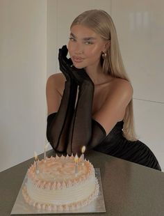 a woman sitting at a table in front of a cake with lit candles on it