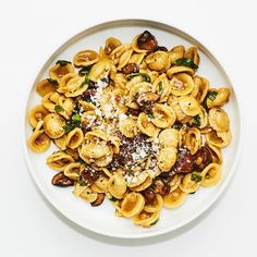 a white plate topped with pasta covered in sauce and toppings on top of it