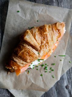 a piece of bread with salmon and cream cheese on it sitting on top of wax paper