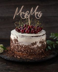 a wedding cake with berries on top and the word mr & mrs spelled in cursive