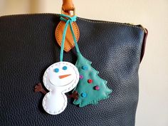 a handbag with a snowman decoration hanging from it's front pocket,