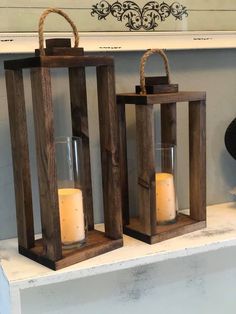 two wooden lanterns sitting on top of a mantle with candles in them next to each other