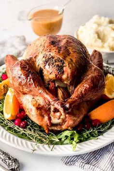 a roasted turkey on a platter with oranges and cranberries