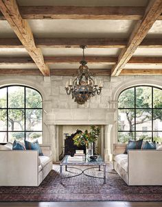 a living room with couches, chairs and a fire place in front of two large windows