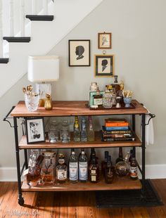 an old fashioned bar cart with liquor bottles on it in front of a stair case