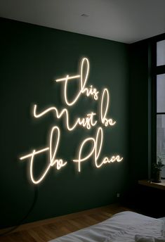 this must be the plan neon sign on wall next to bed in dark green room