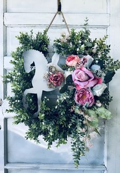 a wreath with flowers hanging on a door