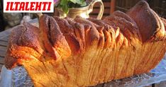 a large loaf of bread sitting on top of a glass platter next to a potted plant