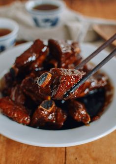 a white plate topped with meat and chopsticks