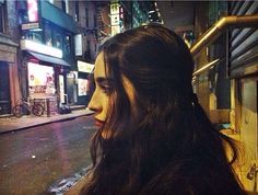 a woman with long hair standing on the street