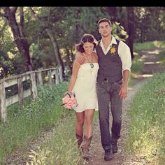 a man and woman walking down a dirt road