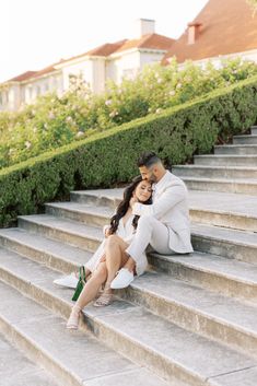 a man and woman are sitting on some steps in front of the stairs with their arms around each other