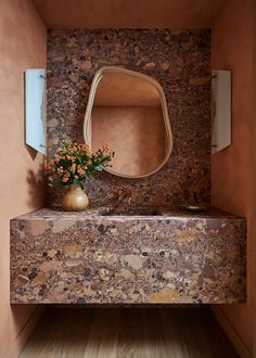 a bathroom with a sink, mirror and flowers on the counter top in front of it