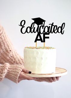 a person holding a cake with the words'educcated af'on it