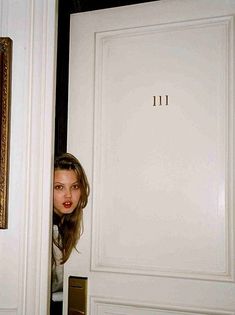 a woman peeking out from behind a door with the number 11 on it's side