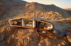 an upside down car in the middle of some dirt and rocks with mountains in the background