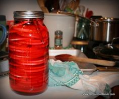 a glass jar filled with red liquid sitting on top of a kitchen counter next to cooking utensils