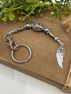 a keychain with an angel wing charm on it sitting next to a potted plant