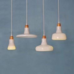 five white and gold hanging lights against a blue wall